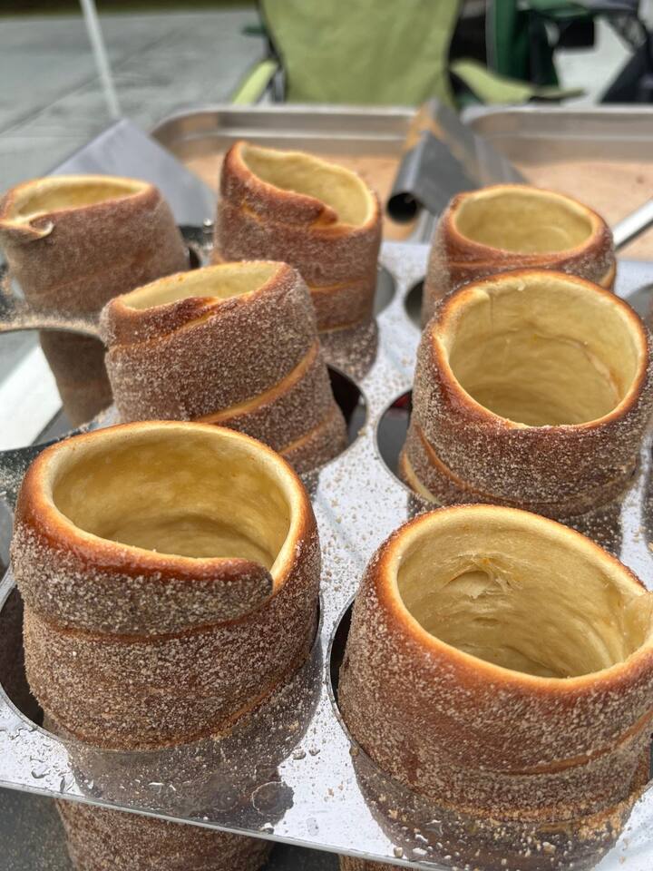 A fresh batch of cinnamon-sugar chimney cakes cooling on a stand